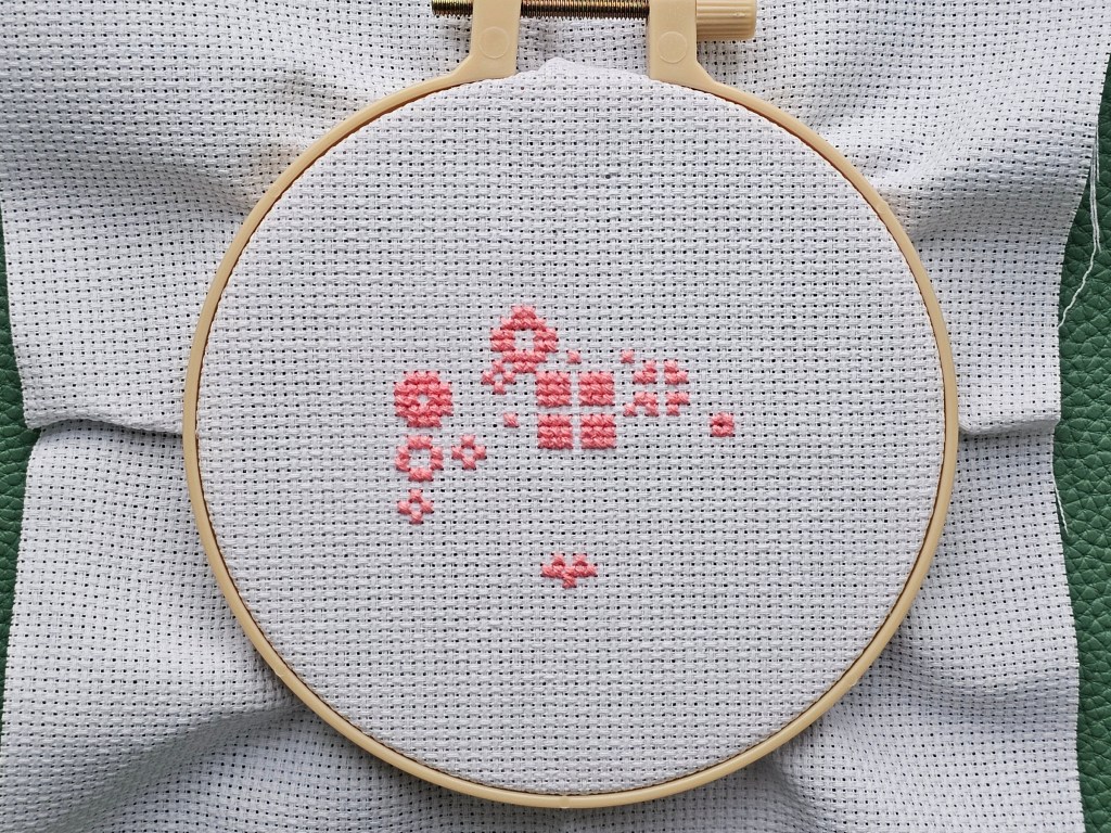 Partially finished mini cross stitch project featuring a floral cat.