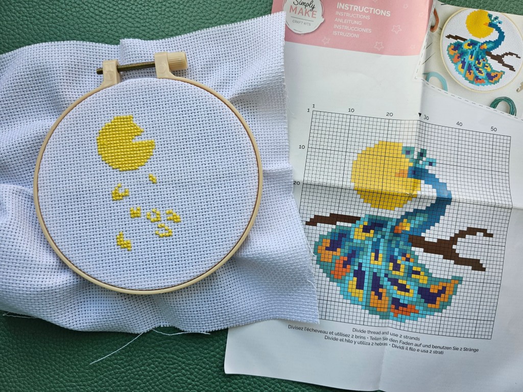 The process of cross stitching a peacock. The yellow areas are done.