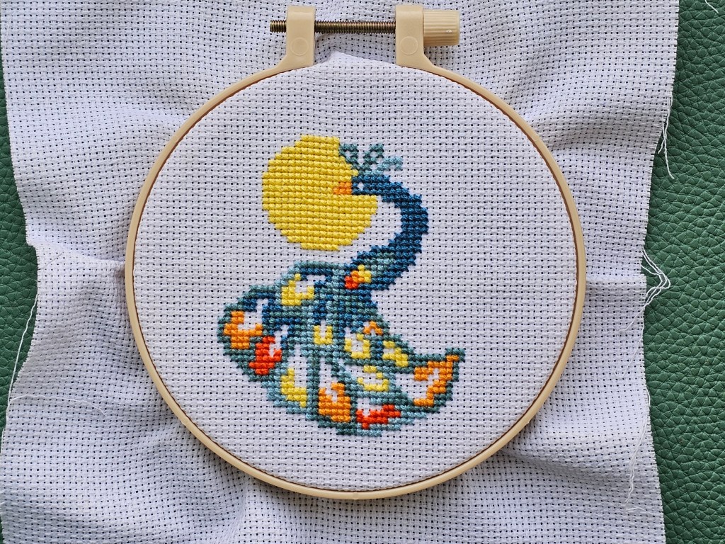 Nearly completed mini cross stitch design featuring a peacock sitting on a branch