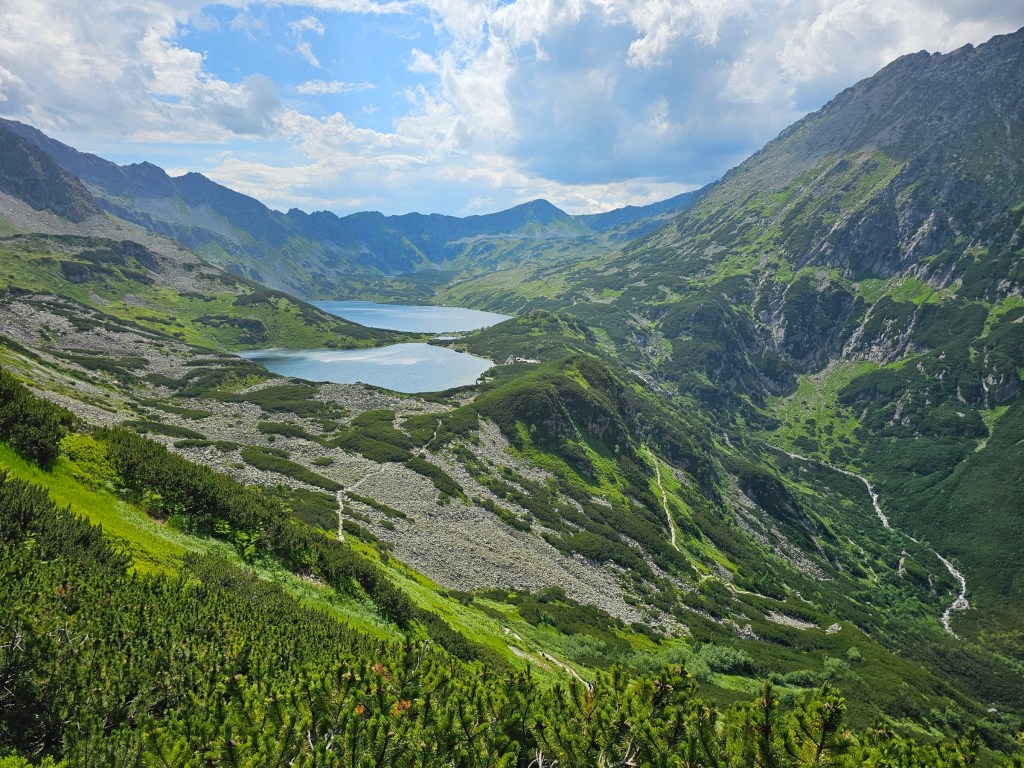 A panoramic view of a couple of large lakes surrounded by tall mountains