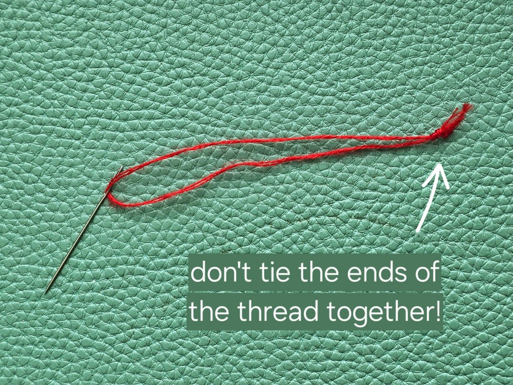 A needle with a thread. The two ends of the thread are tied together