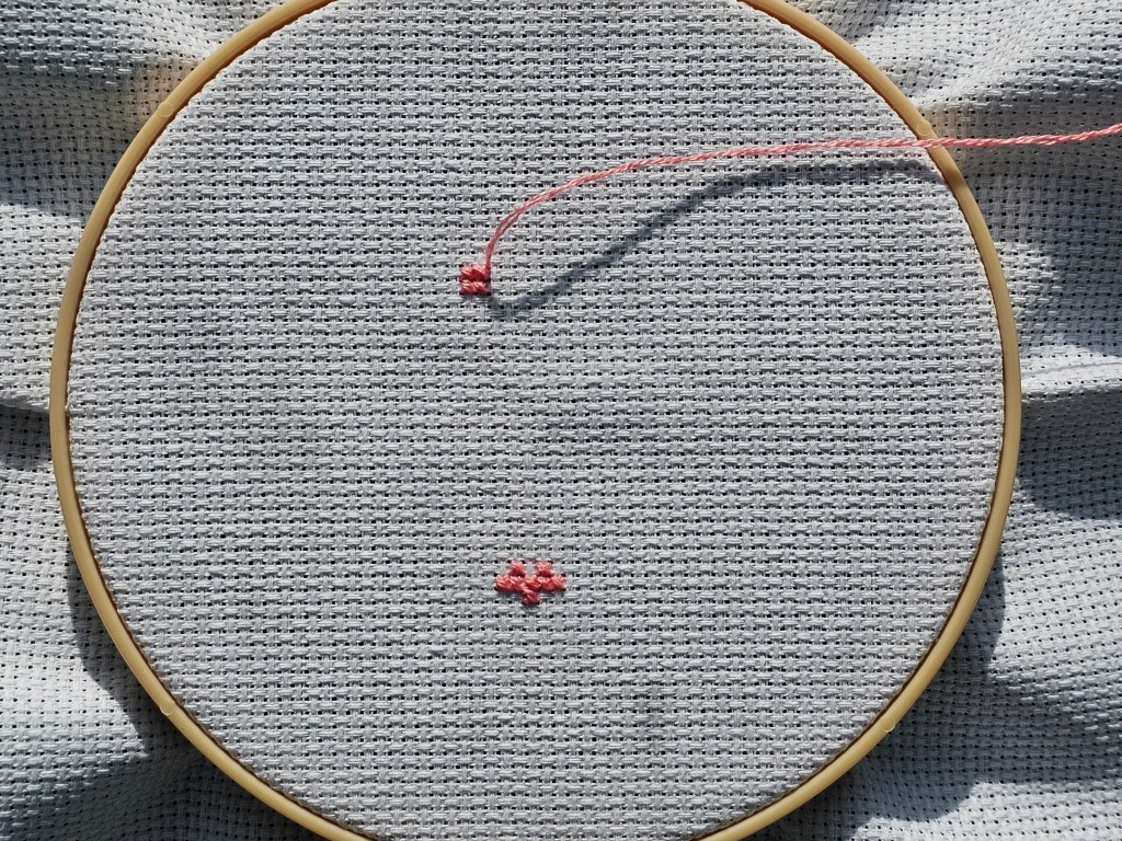 Two small blocks of pink cross stitches on an aida