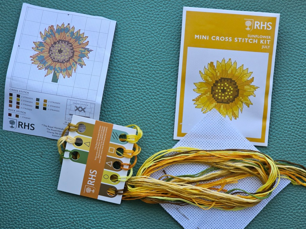 Contents of a mini cross stitch kit for sewing a sunflower design