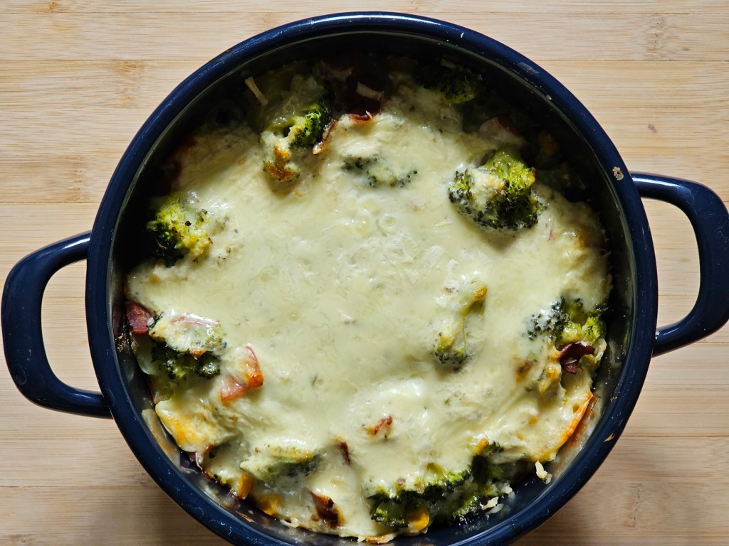 Cooked potato bake with broccoli, sweetcorn and ham arranged in a dish, topped with cheese