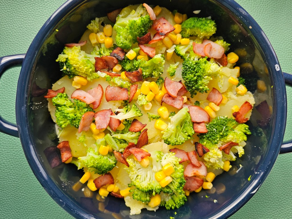 Potato bake with broccoli, sweetcorn and ham arranged in a dish