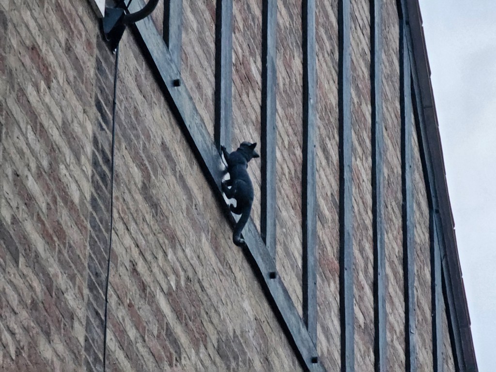 A small sculpture of a cat on a wall of a building.