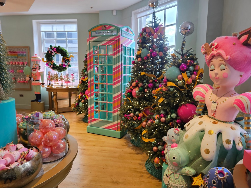 Christmas decorations in Fortnum and Mason, London. There is a traditional London phone booth in pastel colours and Christmas trees with pastel baubles.