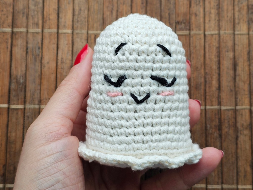 The body of a white crocheted ghost, with embroidered facial details