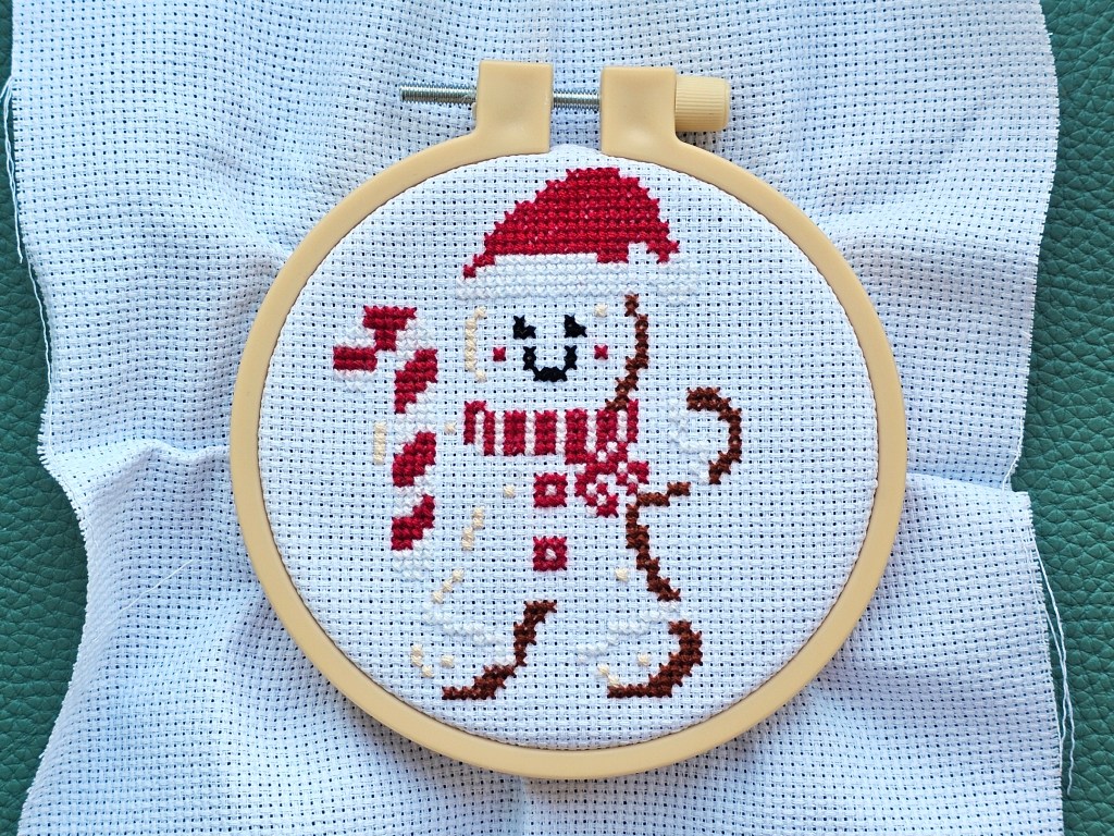 Nearly finished mini cross stitch project featuring a gingerbread man.