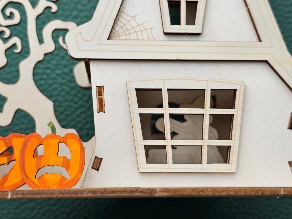 Assembled wooden haunted Halloween house. A silhouette of a witch can be seen through the window.