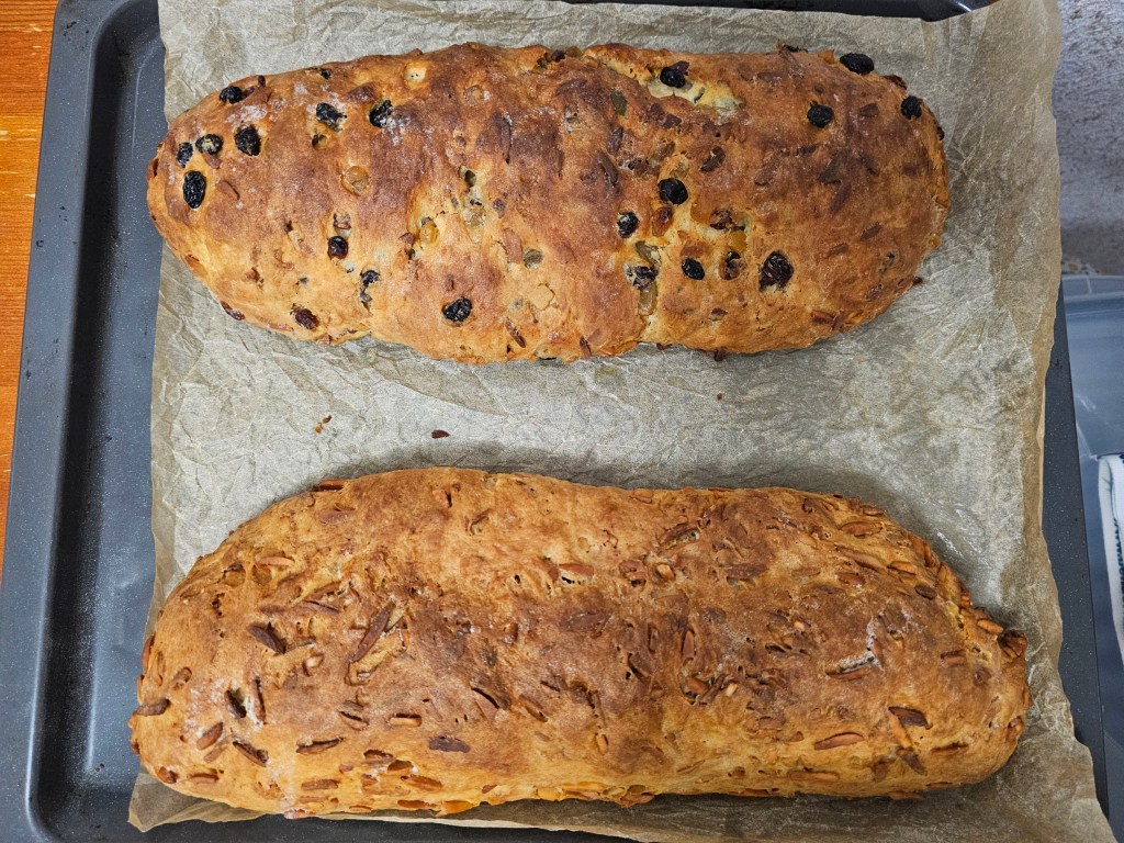 Two baked Christstollen cakes on a baking sheet