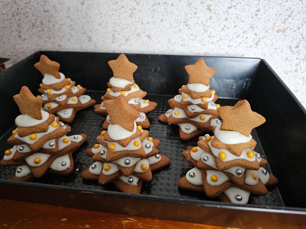 Six Christmas trees made out of gingerbread cookies and icing.