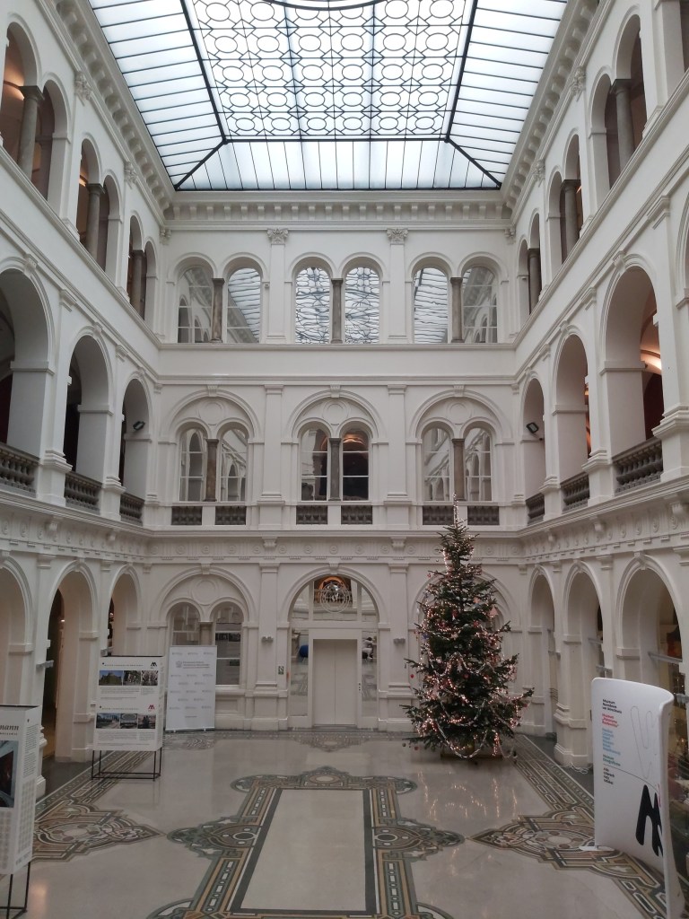The inside of the National Museum in Wroclaw, Poland. There are three floors with arcade windows in a square around the central hall.