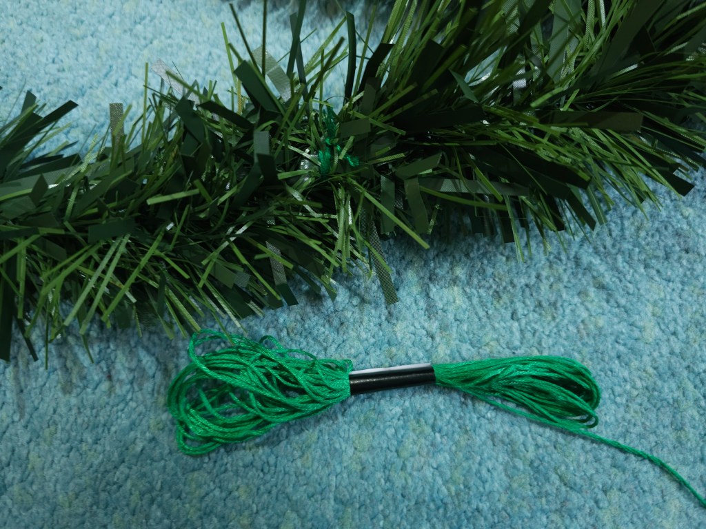The ends of a blank Christmas garland tied together with green thread
