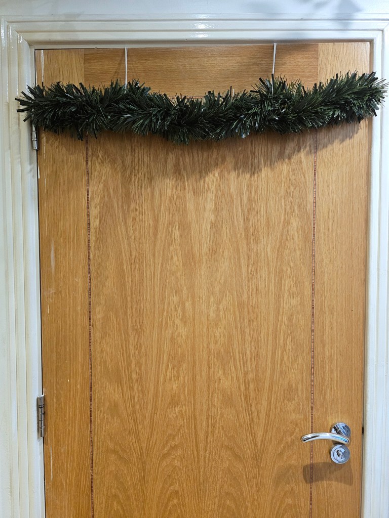 Blank Christmas garland placed on a door in a damage-free way