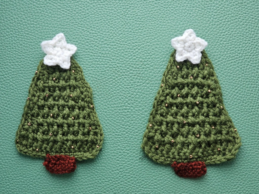 Two finished crocheted trees with brown trunks, white stars and golden beads