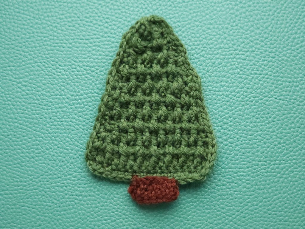 Crocheted green Christmas tree with a brown stem attached.