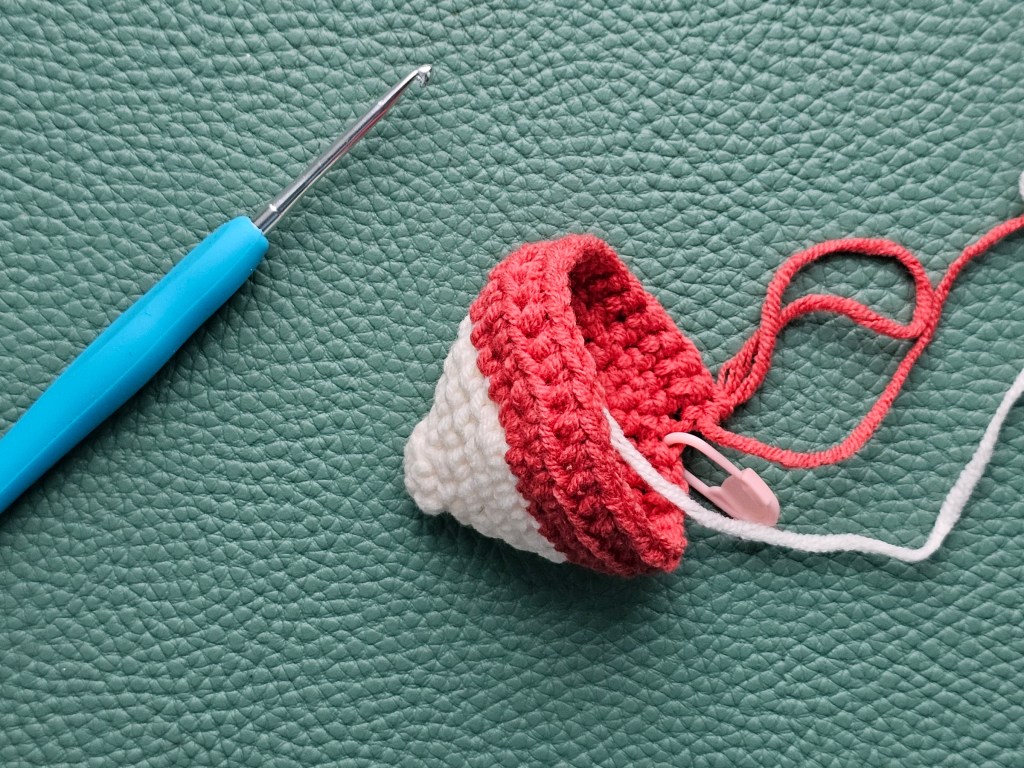 Partially crochetet body of a hedgehog. There are a few white rows that will make the face, and a few rounds of red - the start for the body.