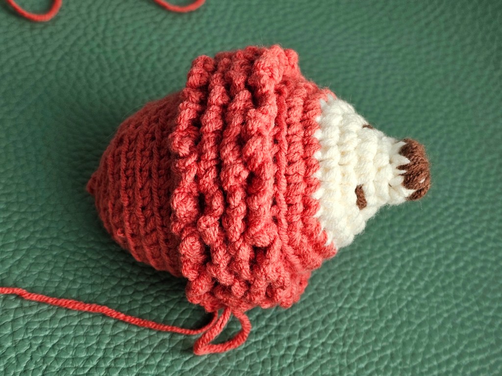 Nearly finished mini crocheted hedgehog. Some rows of spikes are missing.