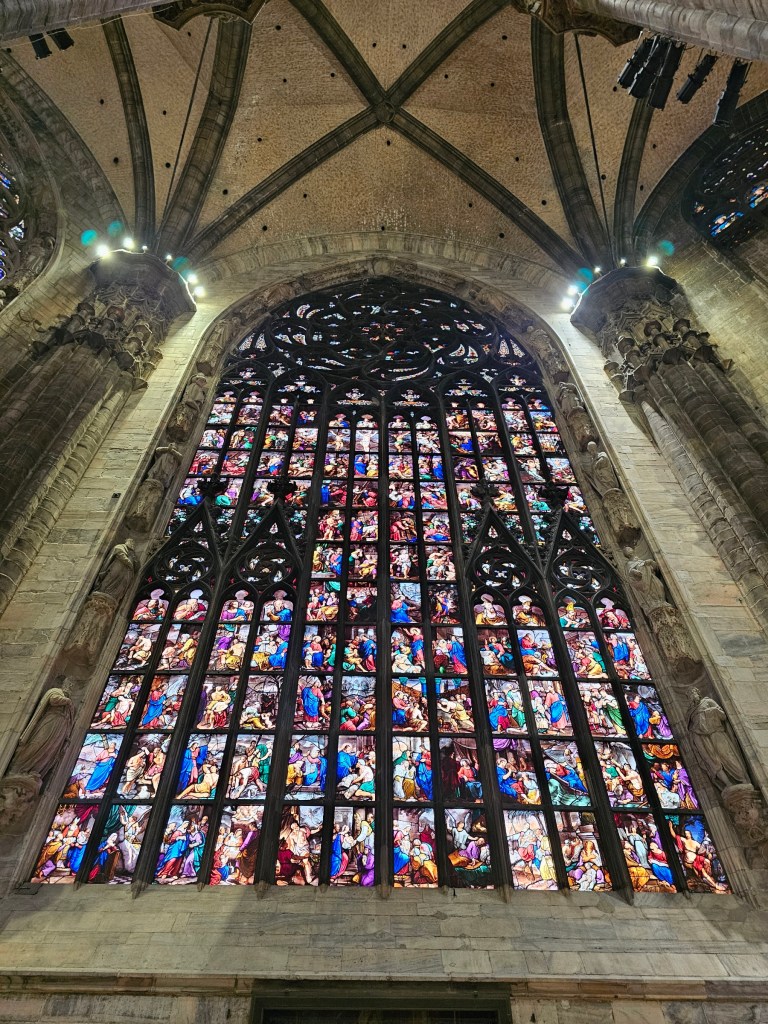 A large stained glass window in Duomo di Milano, made of dozens of panels depicting scenes from the Bible
