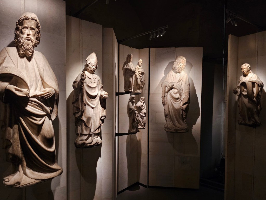 A few statues hanging on a wall in a museum of Duomo di Milano