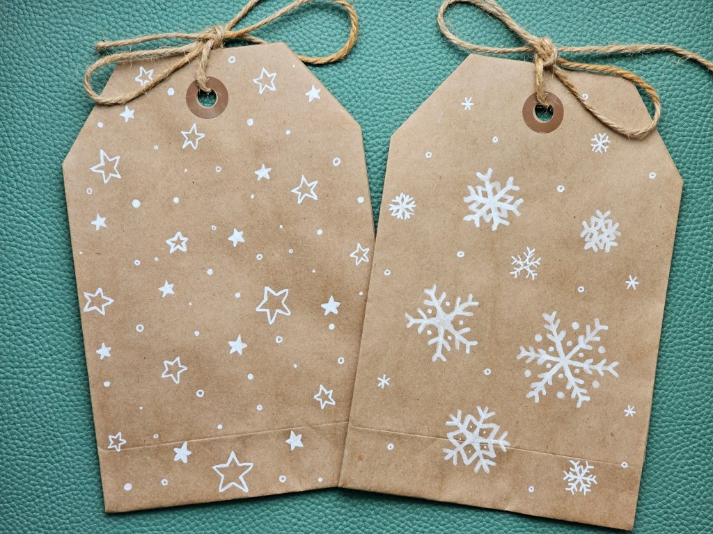 Brown paper gift bags with stars and snowflakes drawn with white pen.