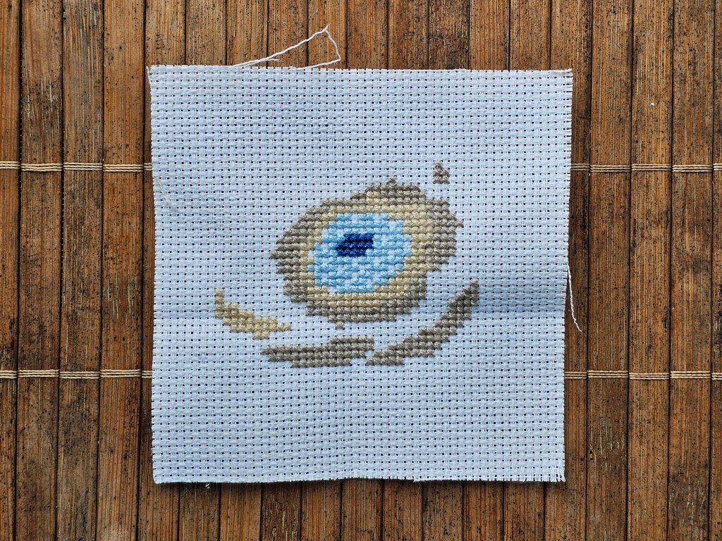 Partially completed cross stitch anemone. Four colours are finished.