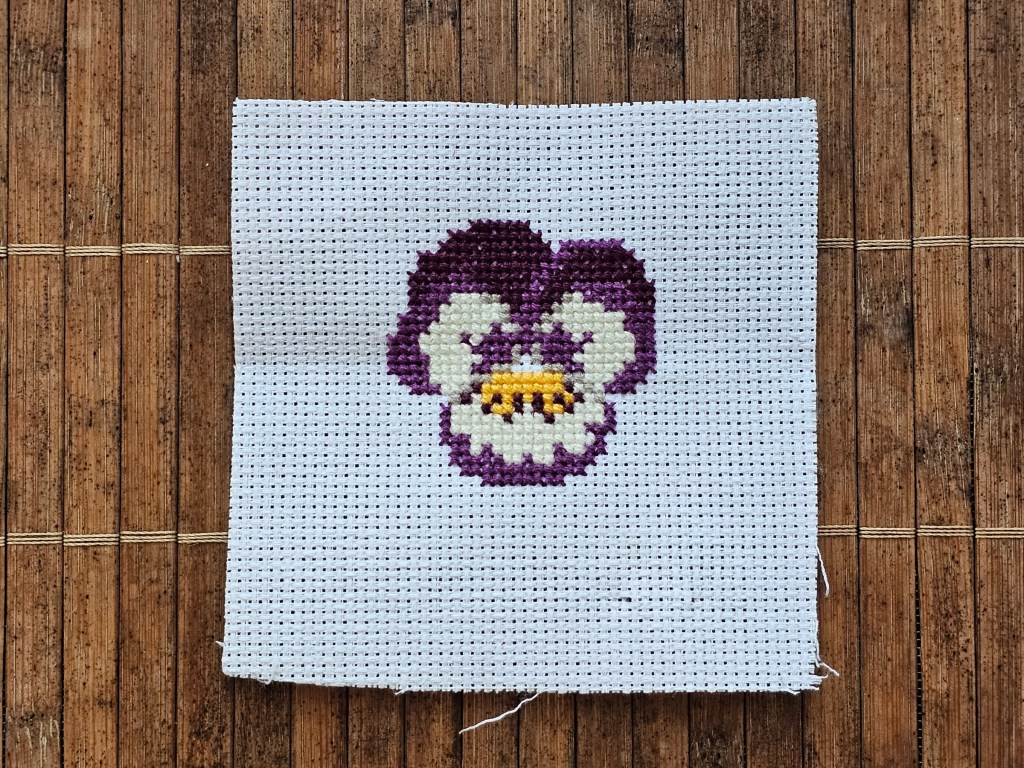 Partially completed cross stitch pansy