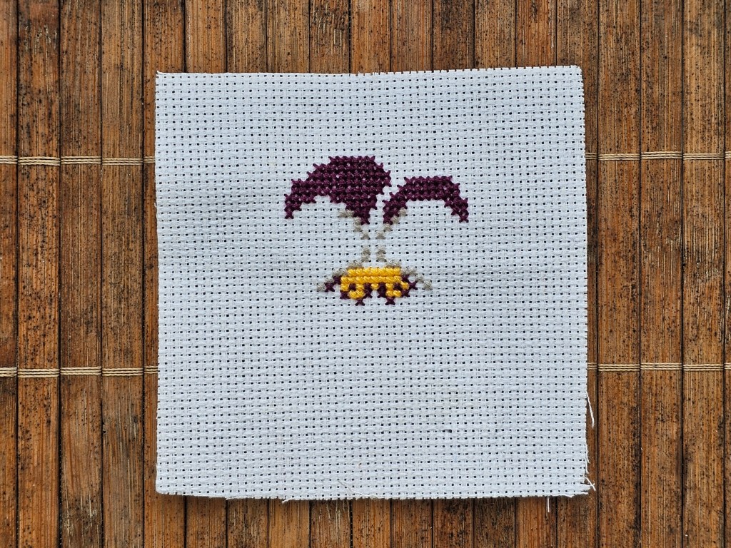 Partially completed cross stitch pansy