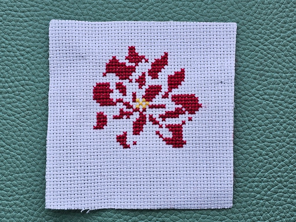 Partially completed cross stitch poinsettia. Two colours are finished.