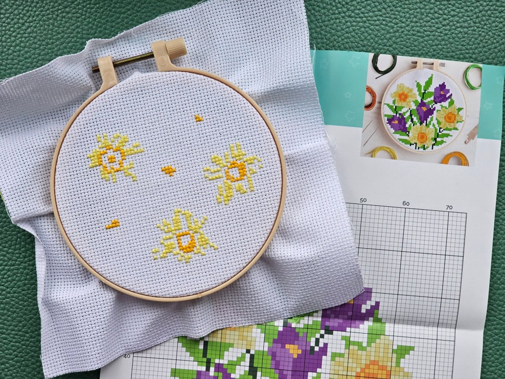 Early stage of a cross stitch project featuring daffodils.