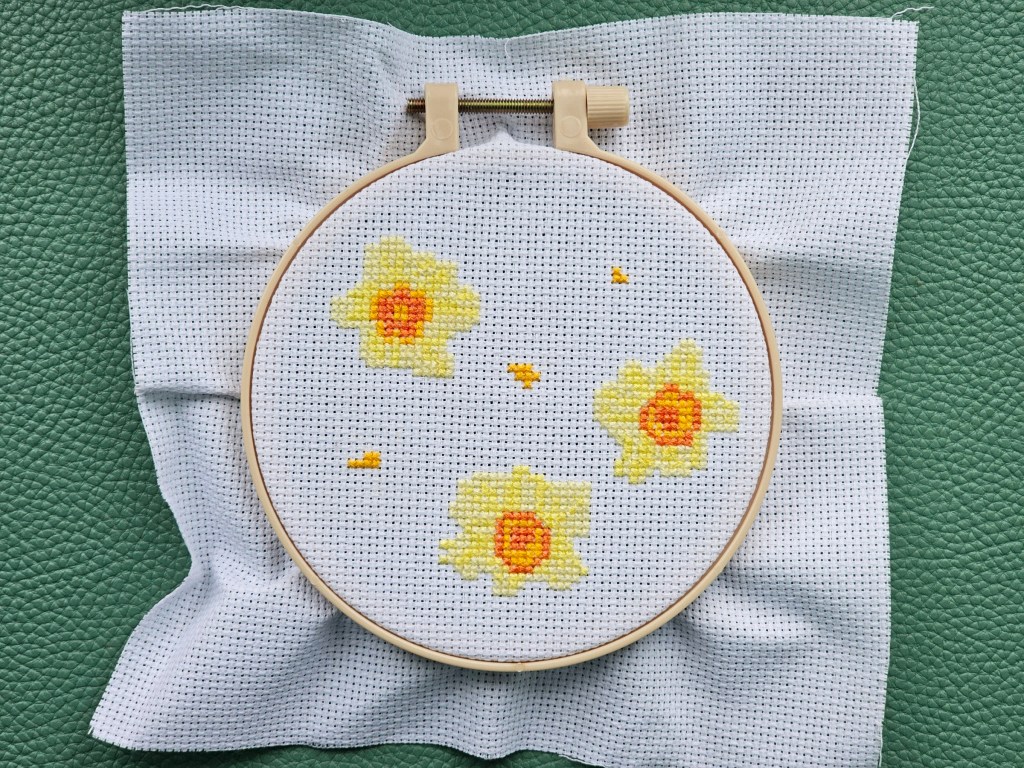 Partly completed cross stitch project featuring daffodils and crocuses. The daffodils are finished.