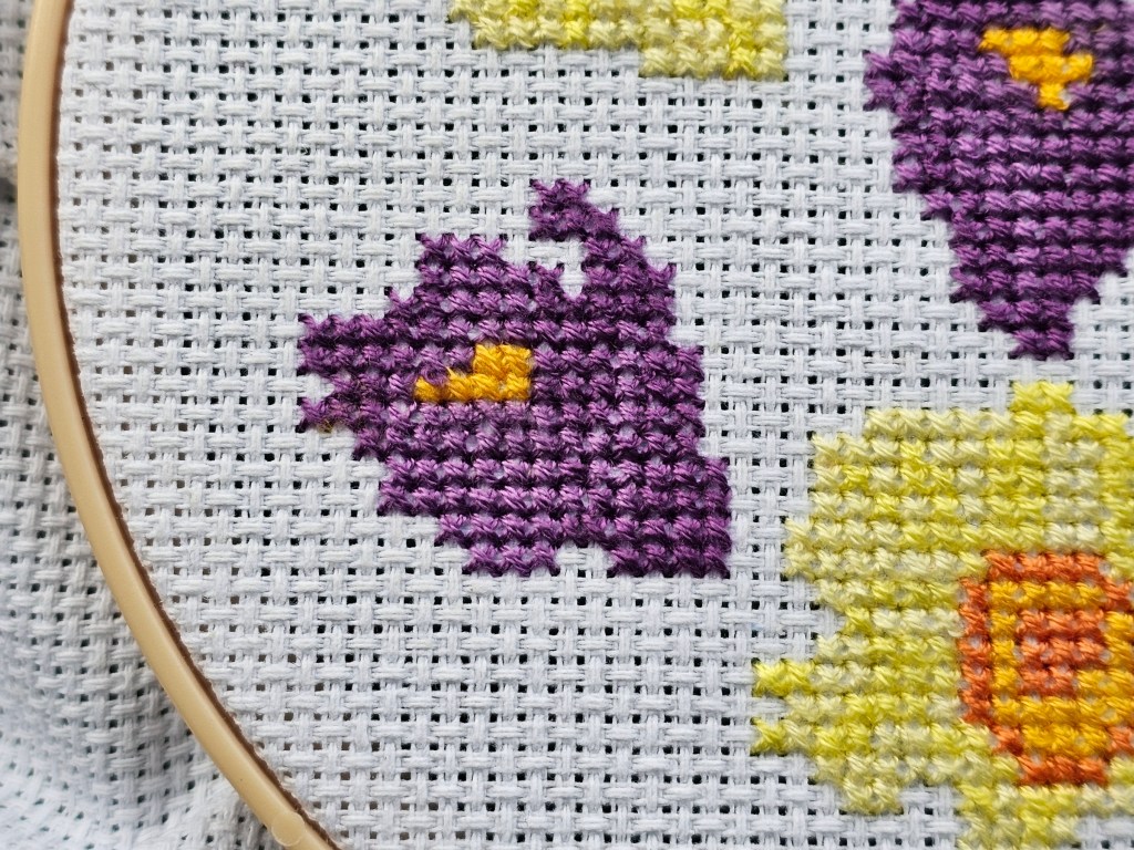 Close up of a cross stitched purple crocus flower, to demonstrate the lack of difference between two shades of purple thread