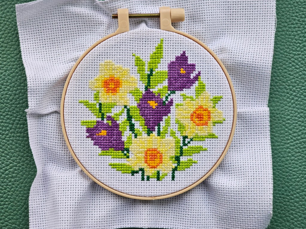 Finished cross stitch project featuring daffodils and crocuses.
