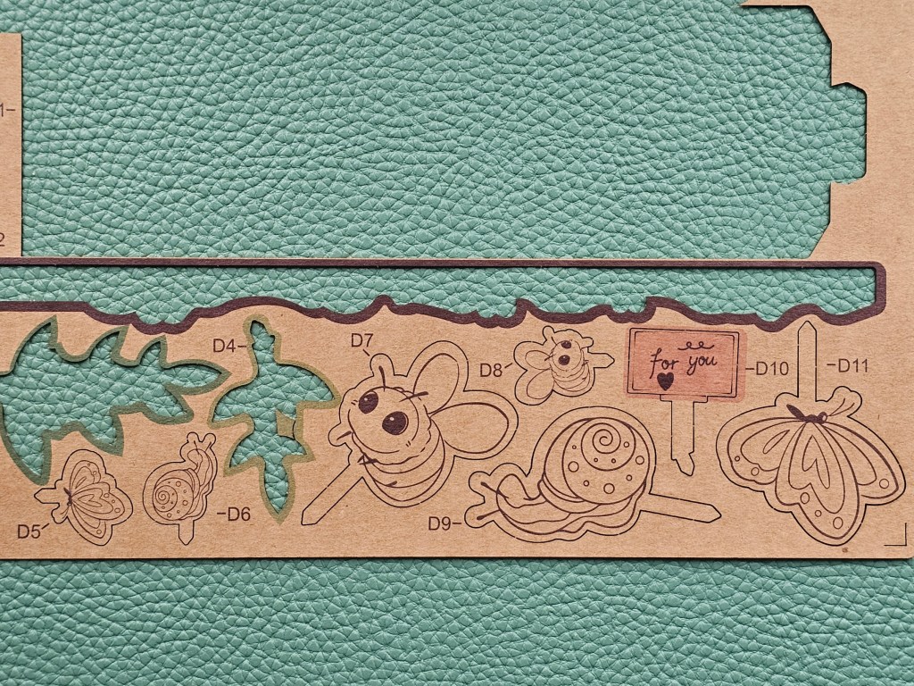 A sheet of brown paper with pre-cut decorations: snails, bees, butterflies