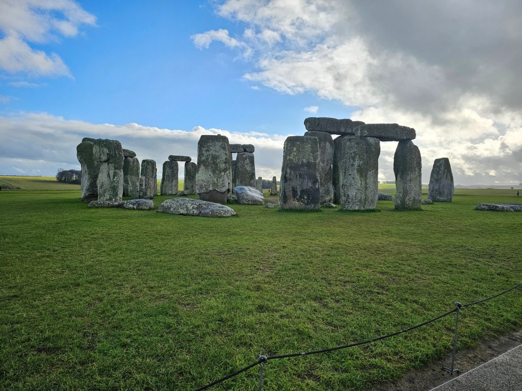 Stonehenge seen on a sunny day. The grass is green and the sky is blue.
