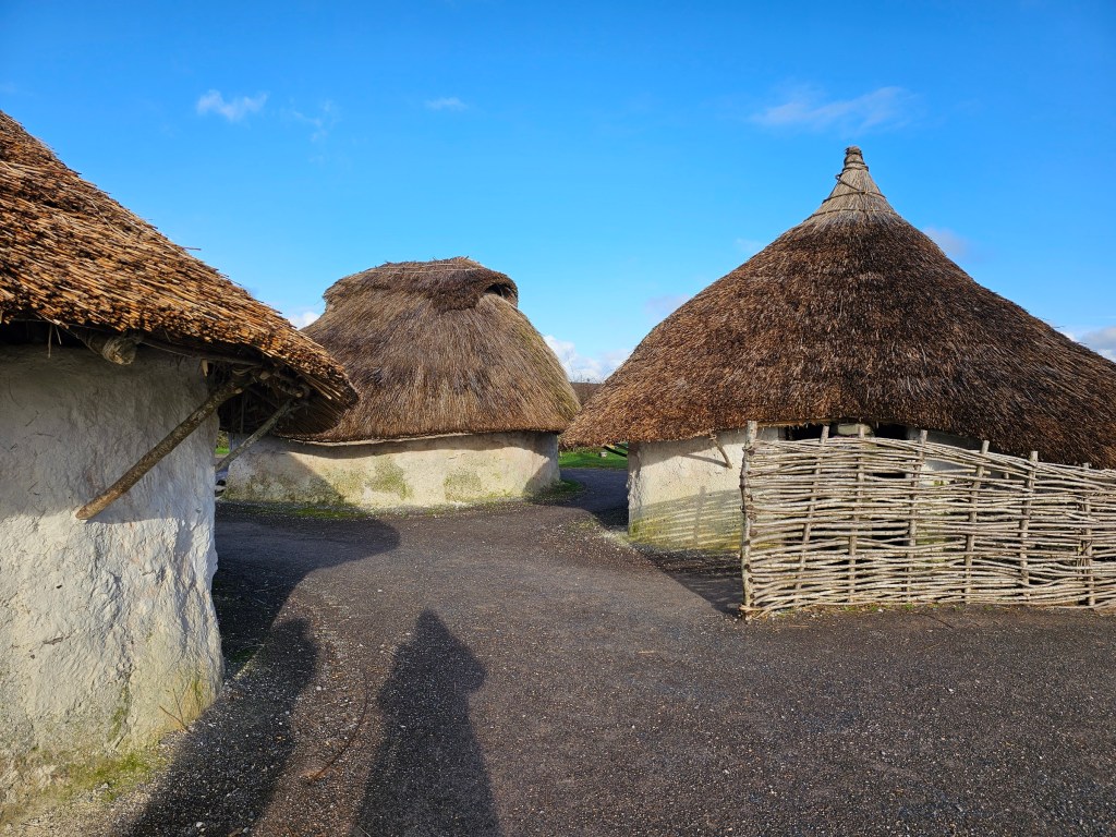 Three life size models of prehistoric huts in Stonehenge settlements