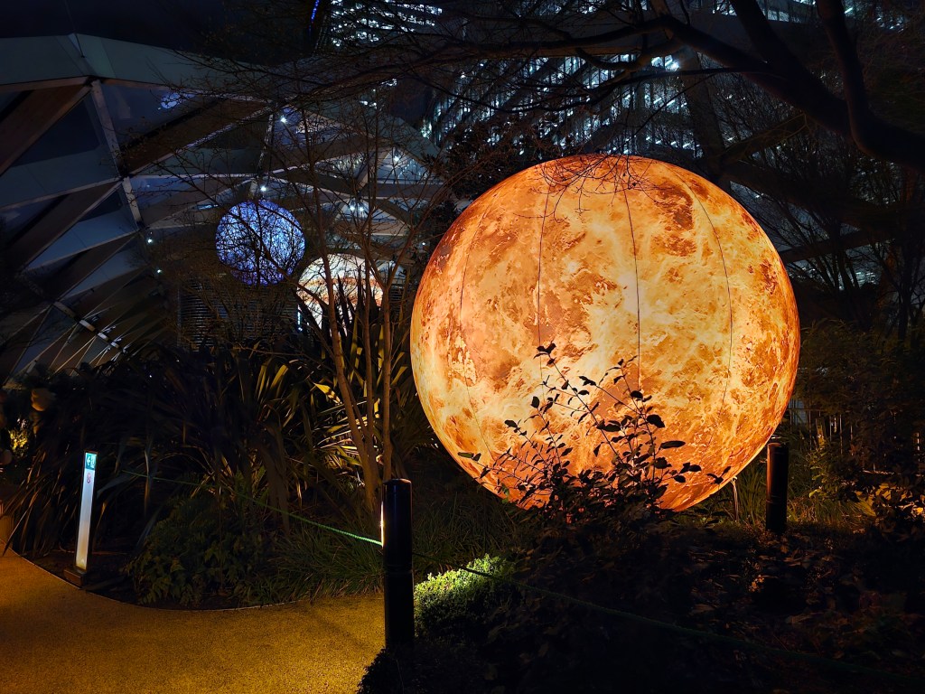 Large installations resembling planets, hanging in a rooftop garden