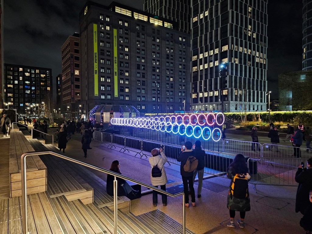 People taking pictures of a light installation featuring illuminated rings