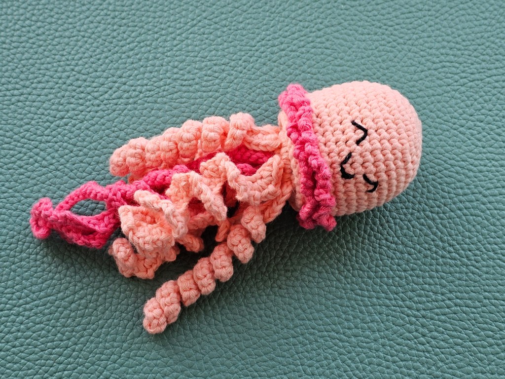 Completed crocheted jellyfish in peach and pink colour