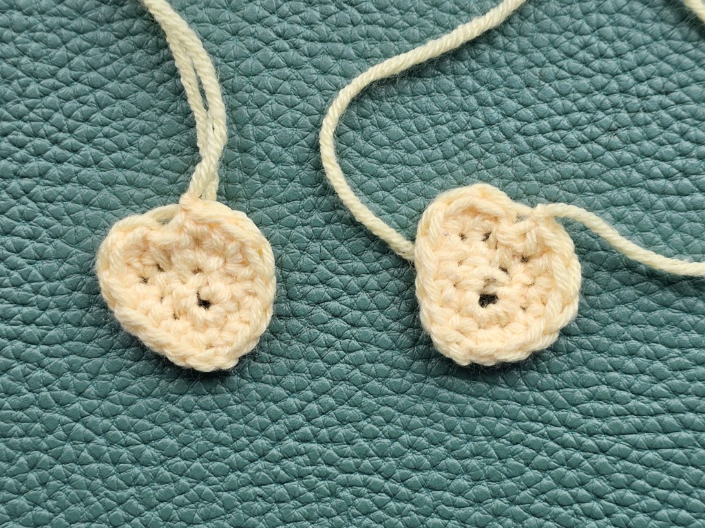 Two small yellow crocheted wings for a chicken