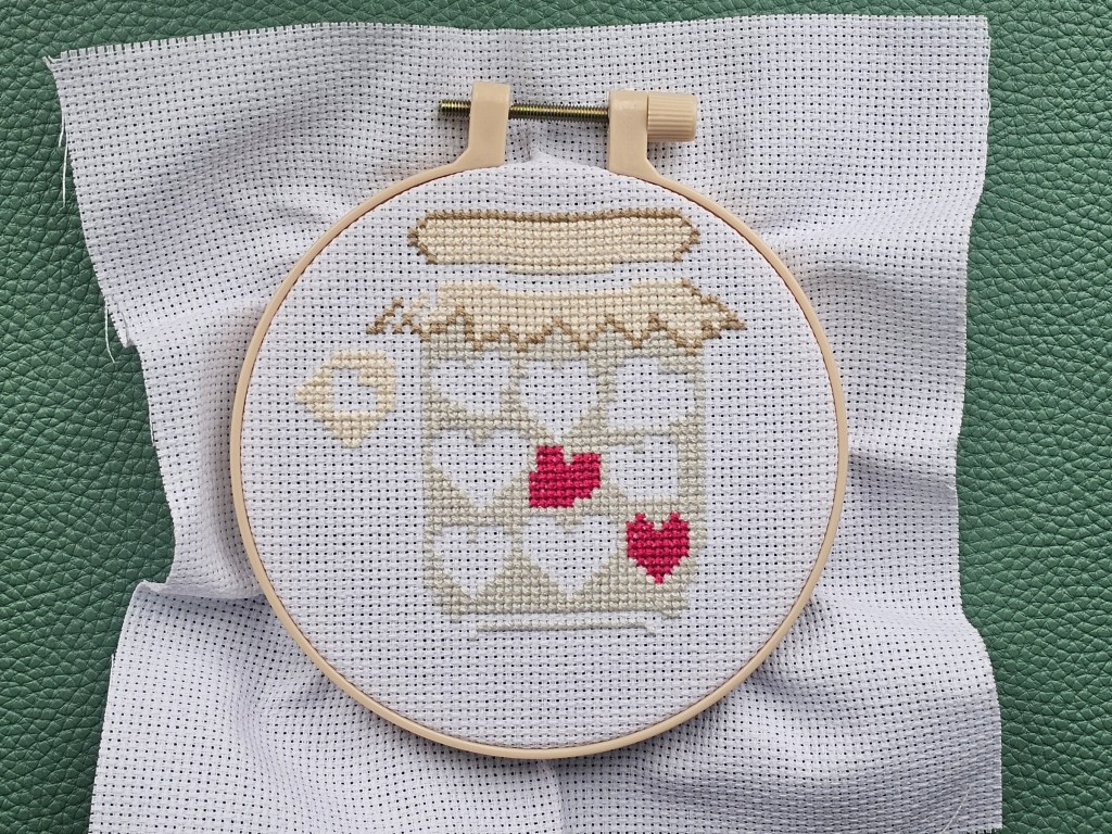 Partially completed cross stitch project featuring a jar of hearts.