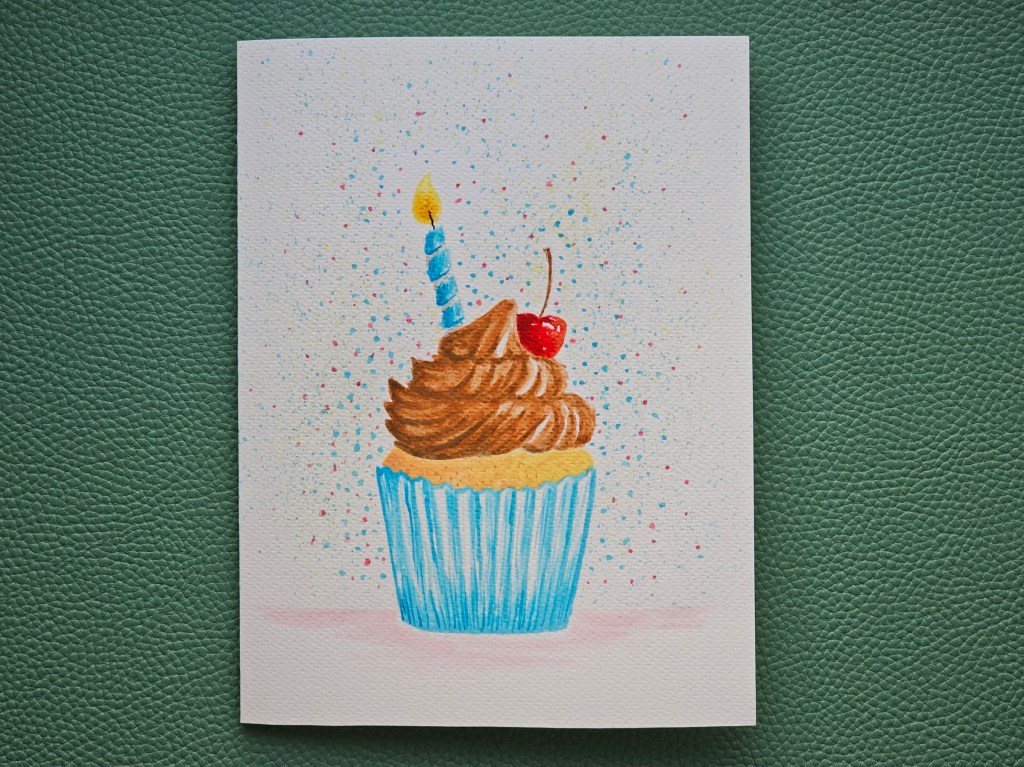 Completed handmade birthday card featuring a watercolour painted cupcake with a candle