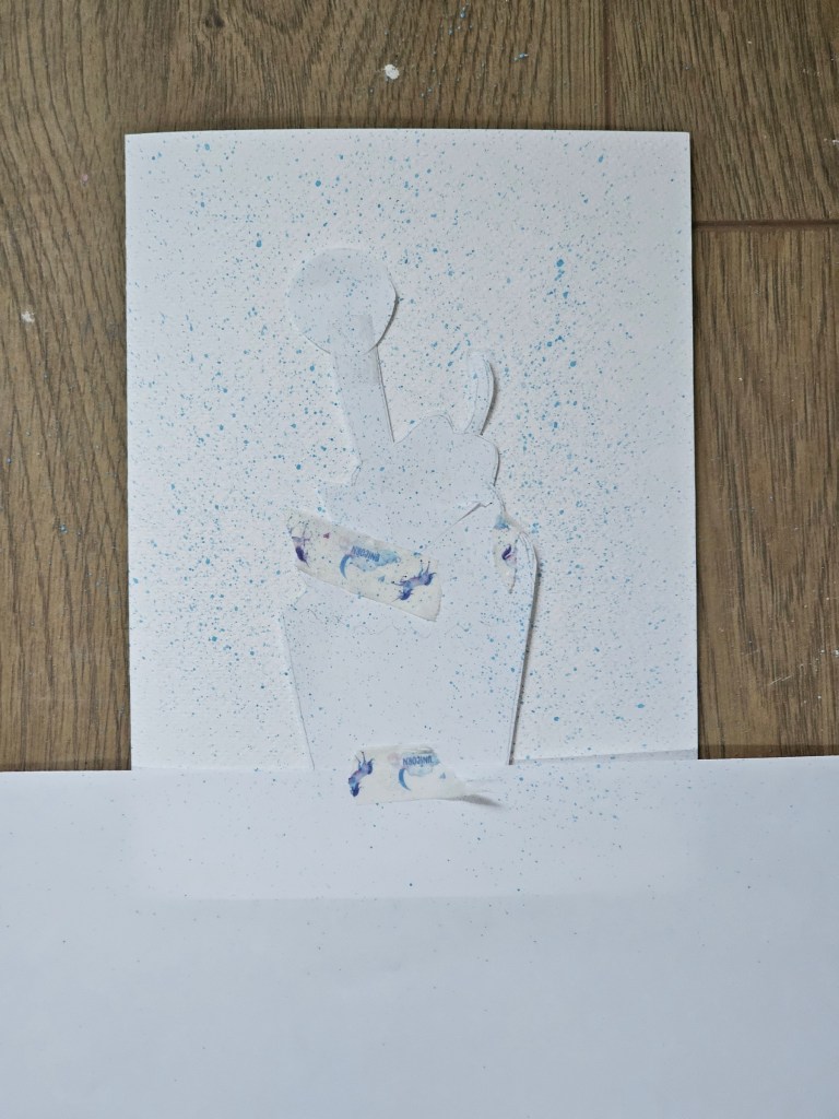 The process of adding sprayed background to a handmade watercolour card