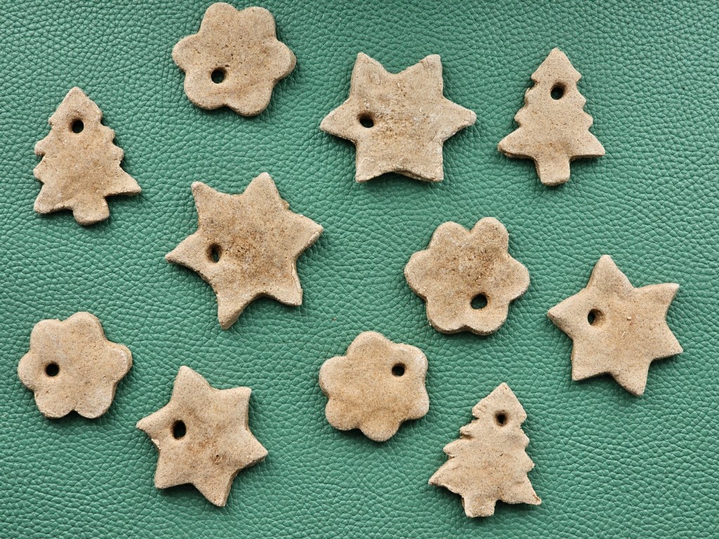 A bunch of cut out gift tags in the shapes of Chrismas trees and stars, made of salt dough