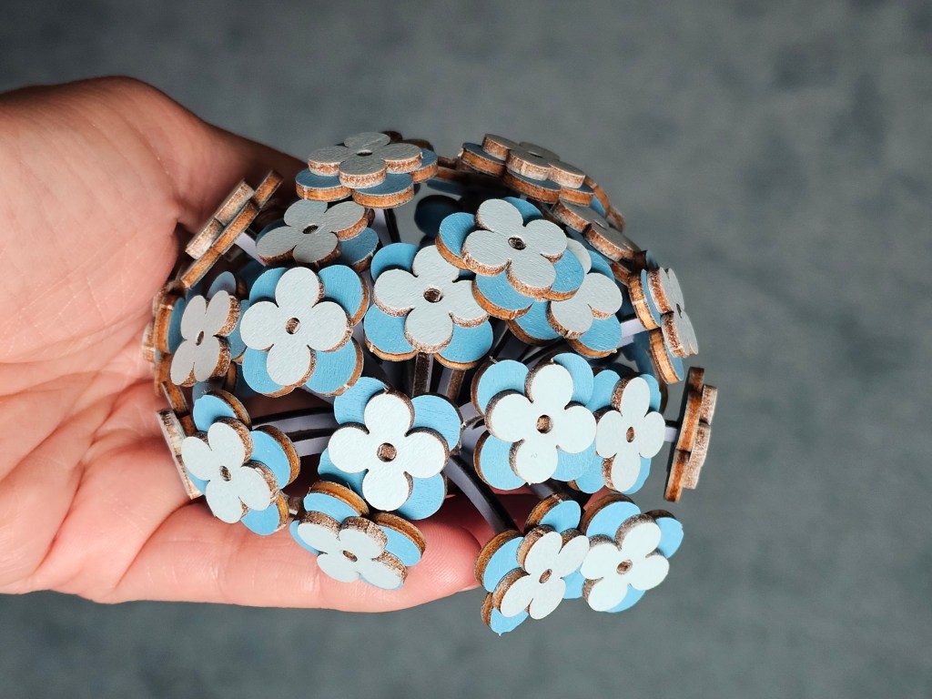 A hand holding a crown of wooden hydrangea flower