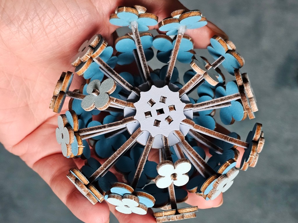 A hand holding a crown of wooden hydrangea flower