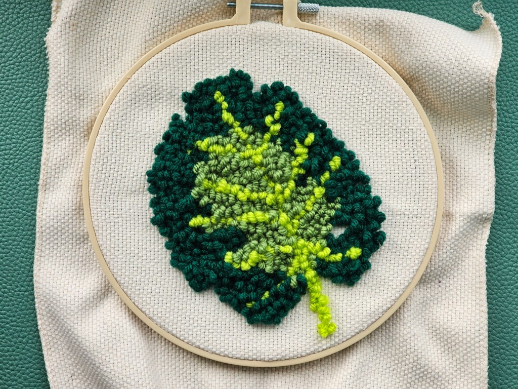 Nearly finished round punch needle canvas featuring a monstera leaf.