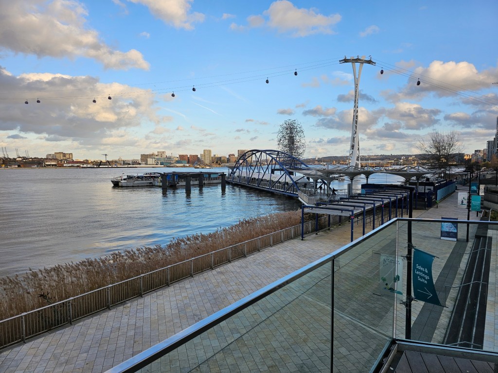A pathway along River Thames in Greenwich, London. The cable car over the river can be seen in the distance