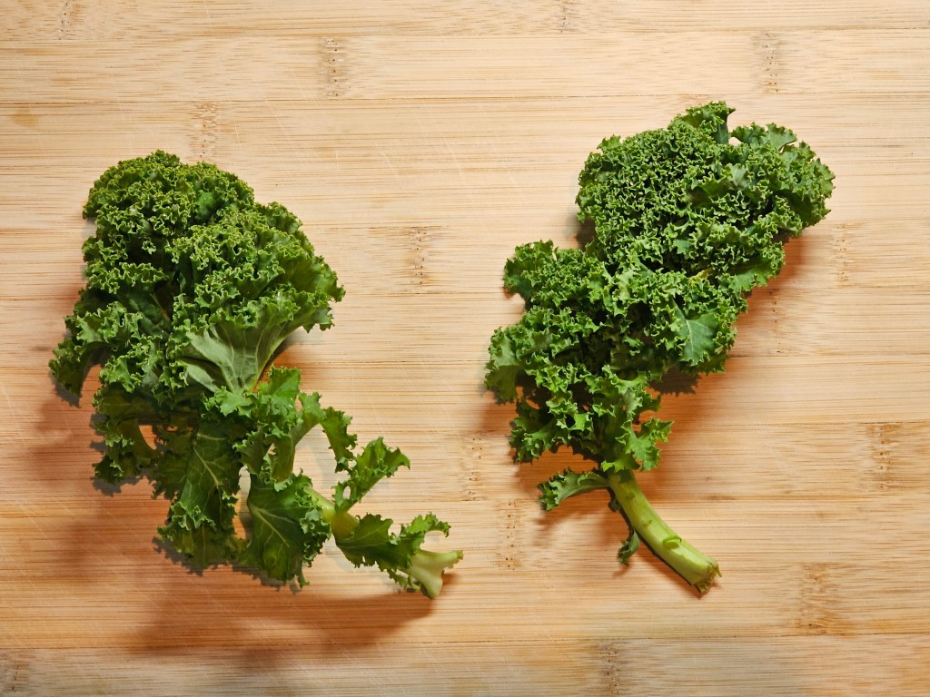 Two large leaves of kale on a wooden board